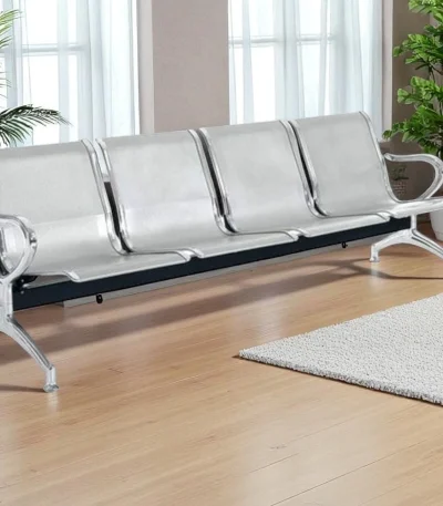 Four-seater stainless steel waiting chair with chrome finish placed in a modern waiting area with wood flooring and indoor plants